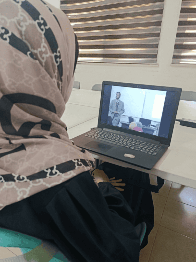 Girl looking at image of Dr. Refaat Alareer on computer screen