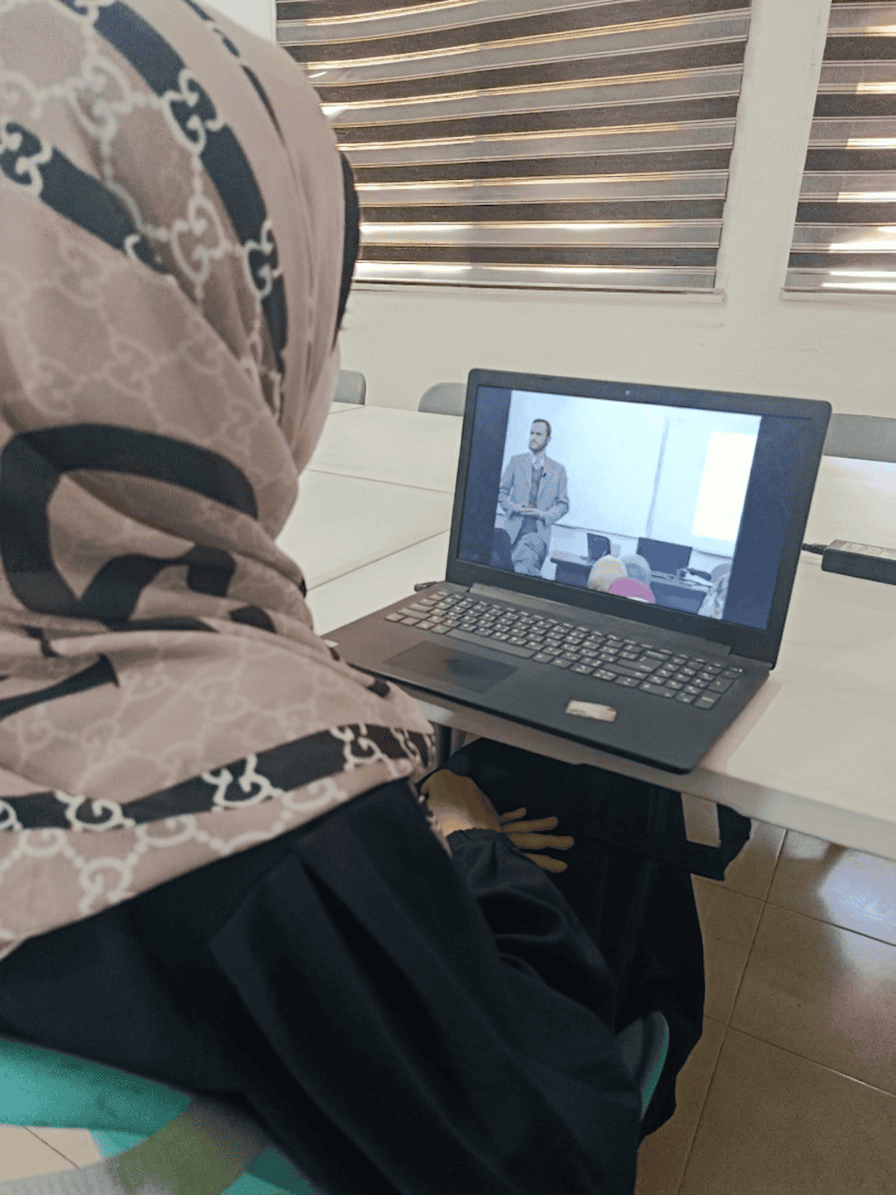 Girl looking at image of Dr. Refaat Alareer on computer screen
