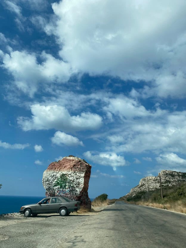 Car near large stone under a blue sky